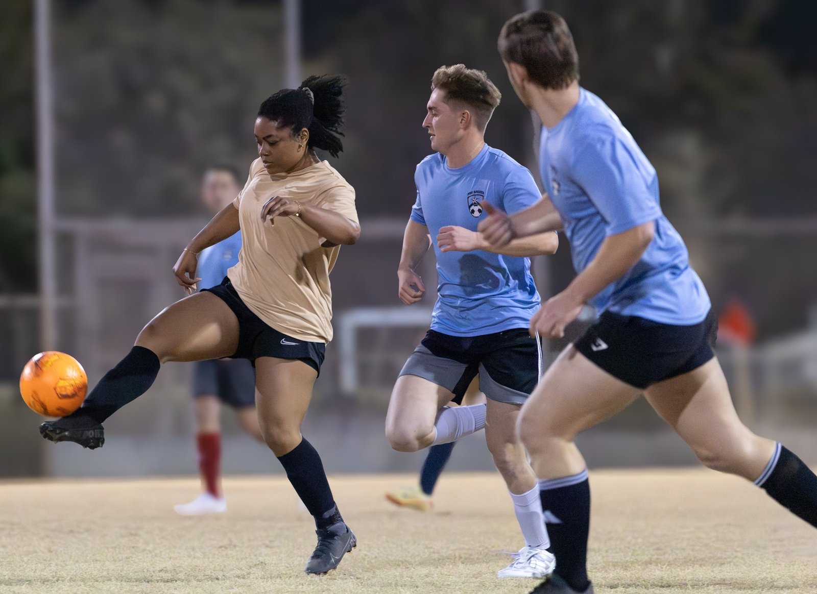 Woman and men chasing the soccer ball
